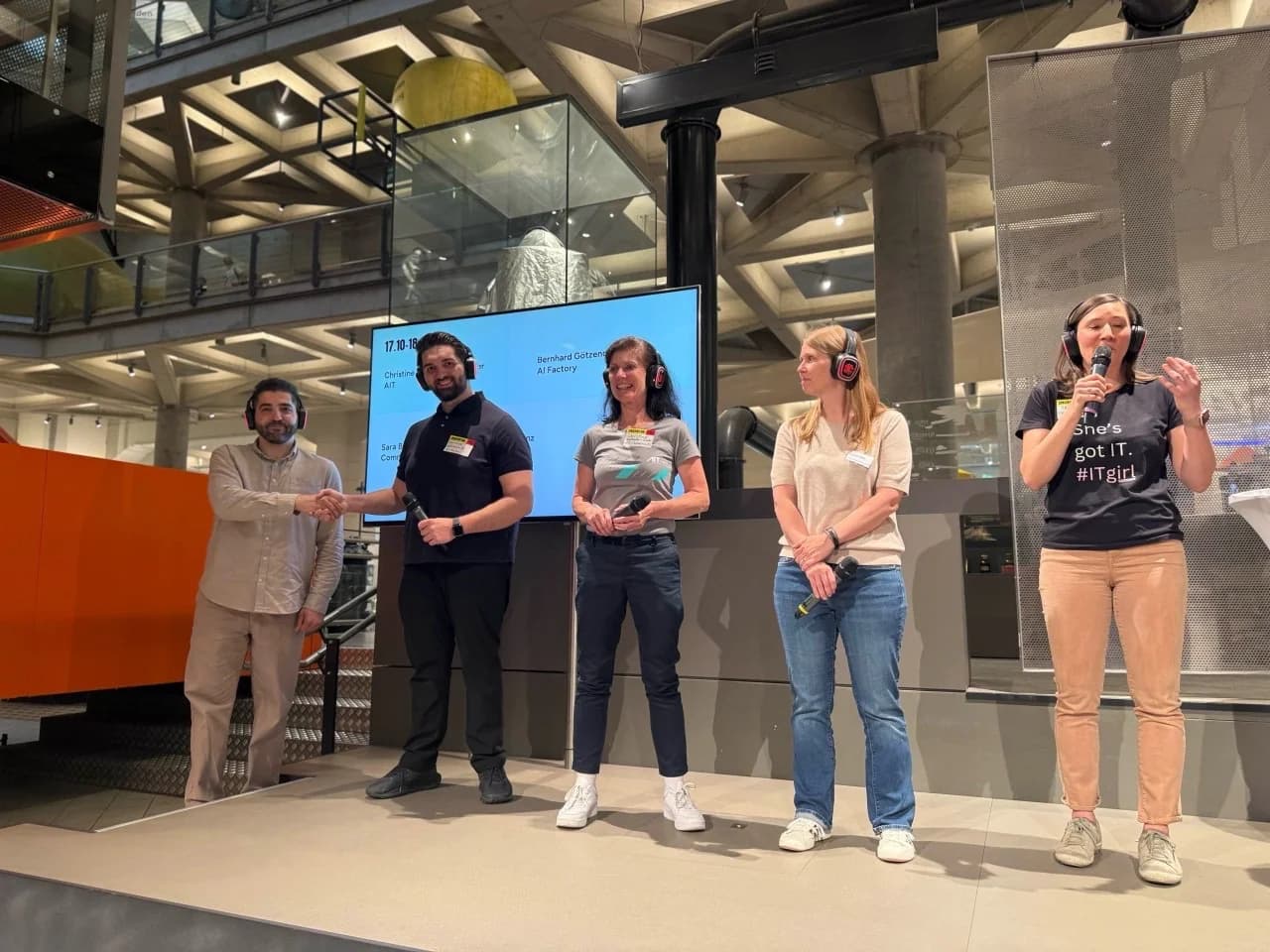 Fünf Personen auf einer Bühne im Technischen Museum Wien, alle mit Funkkopfhörern. Bernhard Götzendorfer, Zweiter von links im dunklen Polo, gibt dem Moderator die Hand. Auf dem Screen dahinter steht sein Name.